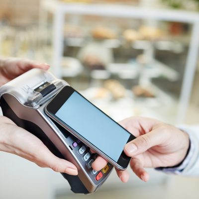 Contemporary client of cafe making contactless payment after lunch